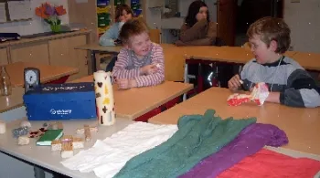 Foto von Kindern an Tischen mit Tüchern, Kerze und Kreuzen