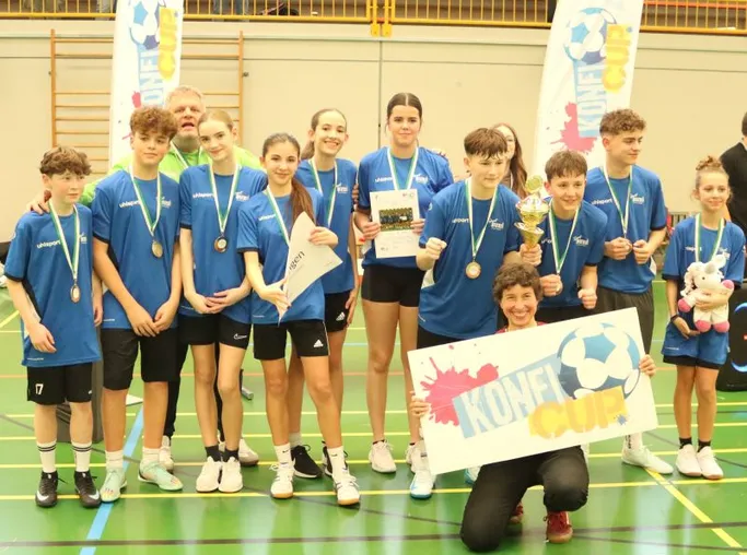 Gruppenbild mit Jugendlichen in Sportkleidung und mit Siegermedaillen in einer Sporthalle.